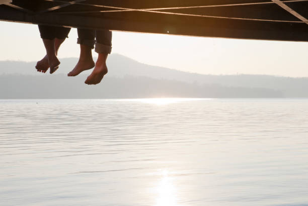 istock A couples' legs dangling from a wooden pier 148323170