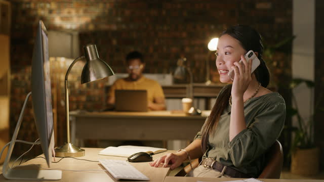 Phone call, Asian woman and night talk with working on a computer of a web designer. Business, communication and mobile planning of a female employee speaking about a website design for a deadline