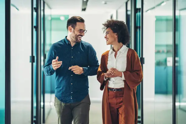 Photo of Couple of business persons walking together and talking