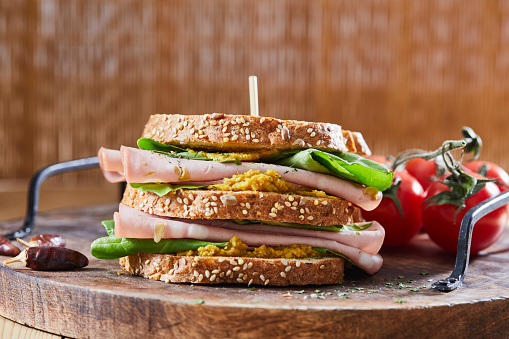 Healthy sandwich for breakfast, with Mortadella and mayo, served on a wooden home, bar or restaurant table, a close up image with a copy space, macro image