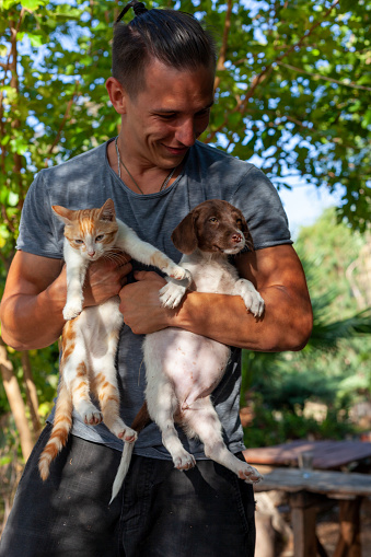 Man holding kitten and puppy