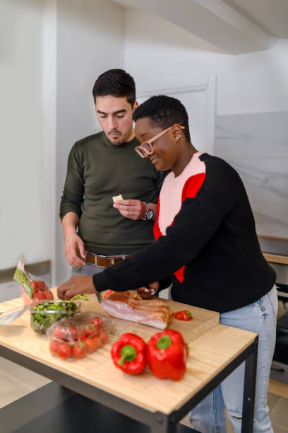 istock A happy young couple is spending a wonderful time together while preparing vegetables and bacon for a delicious dinner. 1483236456