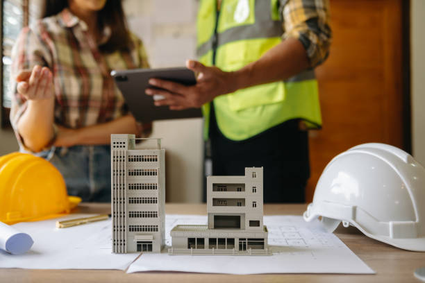istock Two colleagues discussing data working and tablet, laptop with on on architectural project at construction site at desk in office 1483238891