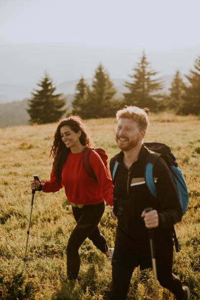 istock Young couple walking with backpack over green hills 1483239174