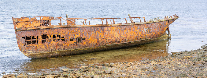 An old whaler wreck in Whalebone Cove off Stanley in the Falkland Islands. Stanley in the background