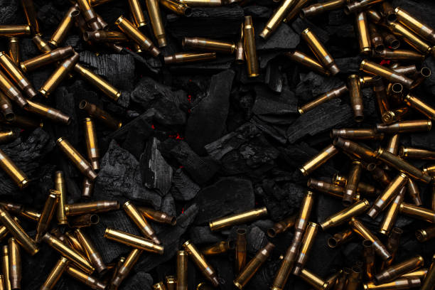istock Empty shells from weapons on black smoldering coals. Consequences of the war. Dark background. 1483240907