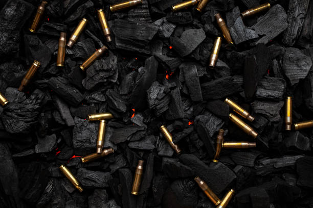 istock Empty shells from weapons on black smoldering coals. Consequences of the war. Dark background. 1483240919