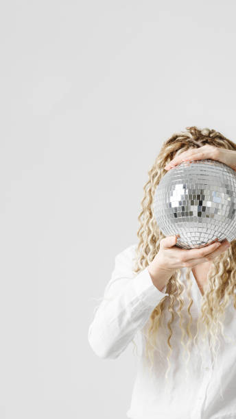 Woman holding disco ball in front of face, no face concept parties, events, dances. Female with long hair dreadlocks hiding behind shiny mirrorball. Minimal creative photo vertical banner, Woman holding disco ball in front of face, no face concept parties, events, dances. Female with long hair dreadlocks hiding behind shiny mirrorball. Minimal creative photo vertical banner, copy space person holding frame over face stock pictures, royalty-free photos & images