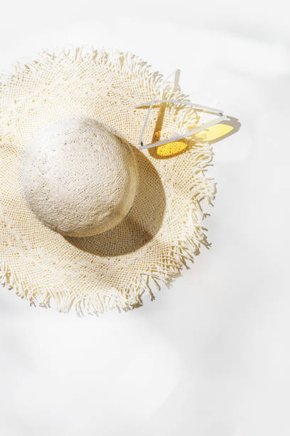 istock Top view summer straw sun hat and yellow sunglasses at sunlight glare, on blurred bokeh light grey background with copy space. Life style summer vacation concept photo, minimal style, pastel 1483243355