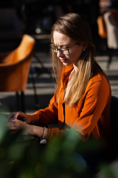 Young businesswoman in a cafe bar or restaurant. Freelancer girl working on laptop and having tea sitting at a window table. stock photo