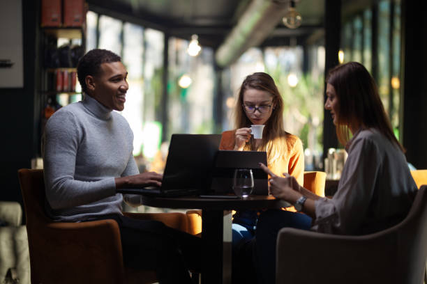 Three multiracial business colleagues having a meeting after work or during coffee break in a restaurant. Friends working at a cafe bar.. stock photo