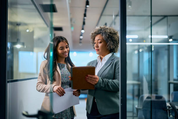 istock Executive manager and her younger coworker using digital tablet while working in the office. 1483244221