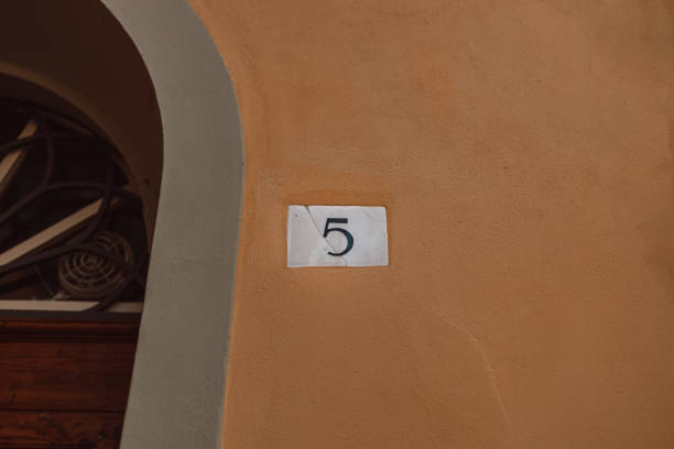 istock Ceramic house number five 5 house number on orange wall background. 1483246734