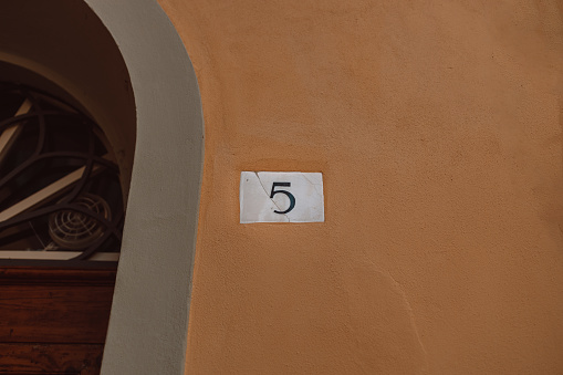 Ceramic house black number five 5 number on orange wall background. . High quality photo