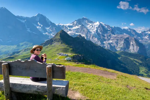 Senior woman hiking the Swiss alps on the top of Mannlichen with beautiful views of the Jungfrau Mountain region.