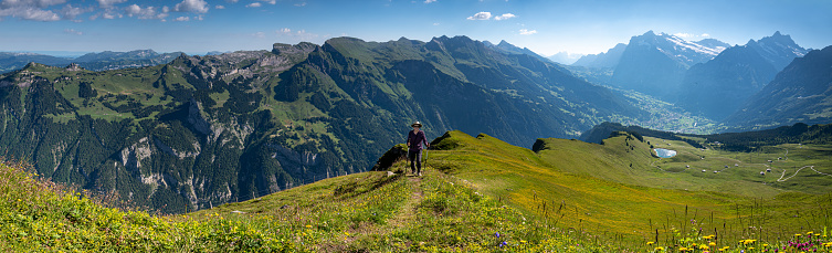 Panoramic view of Senior woman hiking the Swiss alps on the top of Mannlichen with beautiful views of the Jungfrau mountain region.