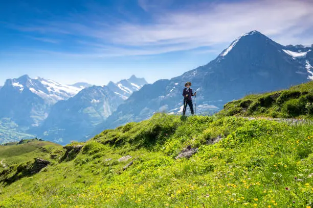 Senior Korean woman on a trail from Kleine Sheidegg to Mannlichen with the Eiger in the background of Snowcapped Swiss Alps