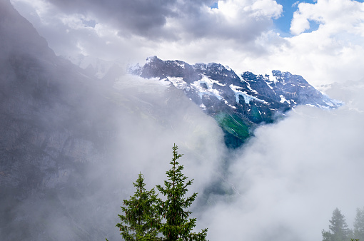 Low clouds over the cliffs surrounding Lauterbrunnen seen from the mountain village Murren. The views of Eiger and Jungfrau are hidden by the clouds