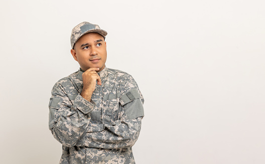 Thinking Asian man special forces soldier standing in studio. Commander Army soldier military defender of the nation in uniform standing on white background.