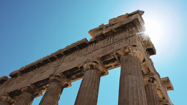 Slow motion shot of Parthenon temple against sunbeams and clear sky