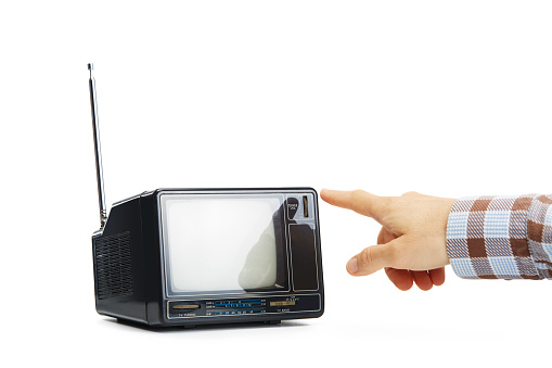 Unrecognizable person changing the channels on old vintage television on white. Hand touching the retro portable tv receiver button isolated on white background