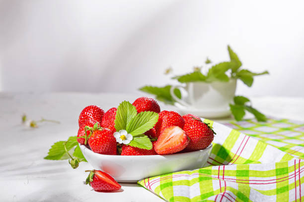 istock Fresh strawberries in a bowl on white stone table. Still life with selective focus and copy space for text 1483262090