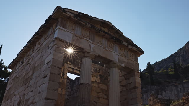 Sun shining through Athenian Treasury against clear sky