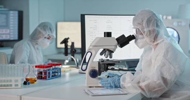 istock Scientist, hazmat suit and microscope in lab analysis for medical research for particle, molecule or virus. Woman, tools and study in laboratory with ppe for dangerous bacteria for science innovation 1483265750