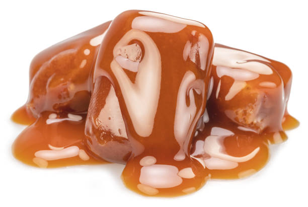 istock Caramel candies covered with melt caramel isolated on white background. 1483265759
