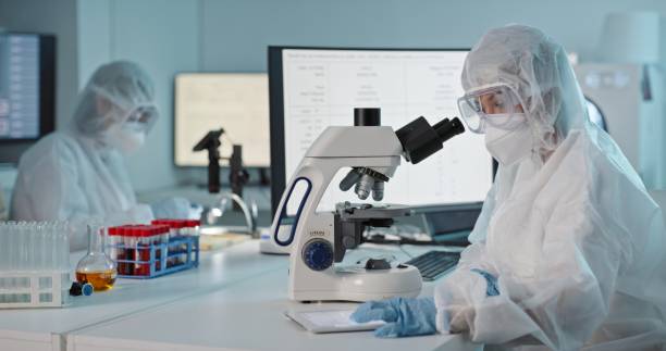 istock Microscope, medical research and protection gear in a laboratory with scientist worker doing work. Virus expert, working and safety in science lab with biohazard suit and staff with mask from risk 1483266791