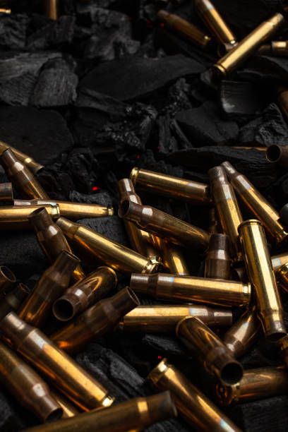 istock Empty shells from weapons on black smoldering coals. Consequences of the war. Dark background. 1483267408