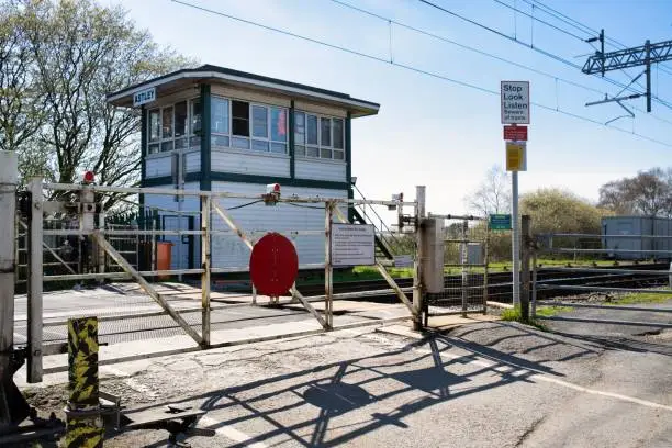 Level crossing gates on the train tracks and signal box Astley Barton Moss Manchester