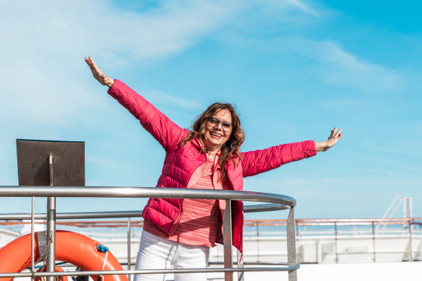 beautiful happy middle aged woman having fun on the deck of a cruise ship stock photo
