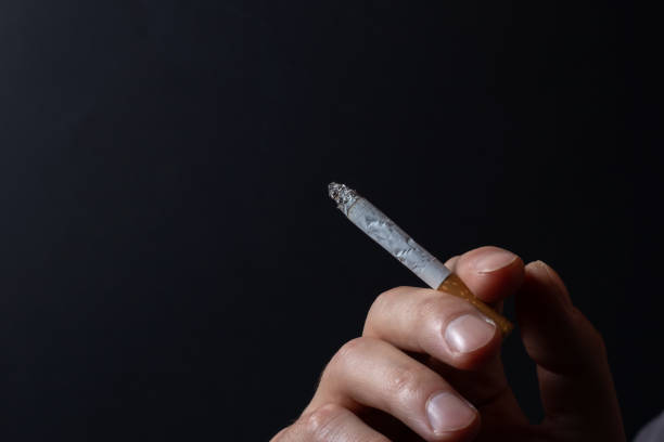 istock Hand with burning cigarette and smoke on black background 1483277519