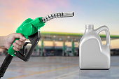 Engine oil nozzle against and bottle of engine oil. gas station blurred background. Energy fuel concept
