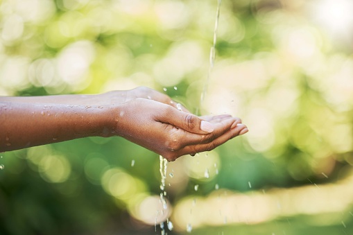 Hands, water and cleaning for hydration, wash or hygiene in care, splash and wellness in nature. Hand of person washing with clean natural aqua liquid to prevent germs and remove dirt for freshness