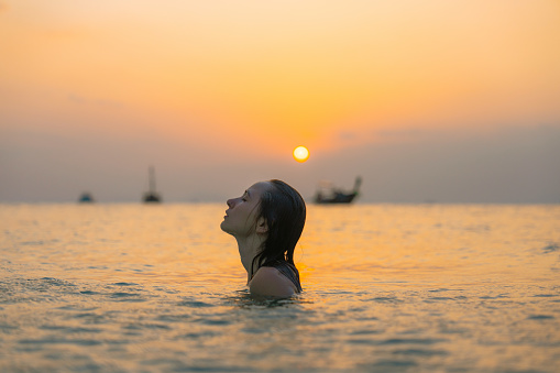 Young  woman swimming at sunset in Andaman sea