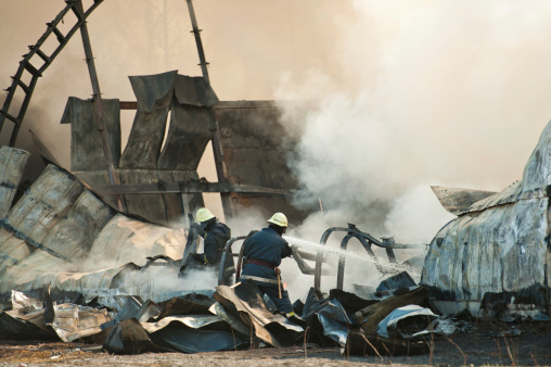 Firemen attending the scene of a fatal airplane crash with thick gray acrid smoke.