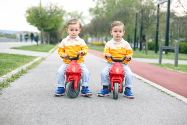Twin brothers driving toy motorcycles stock photo