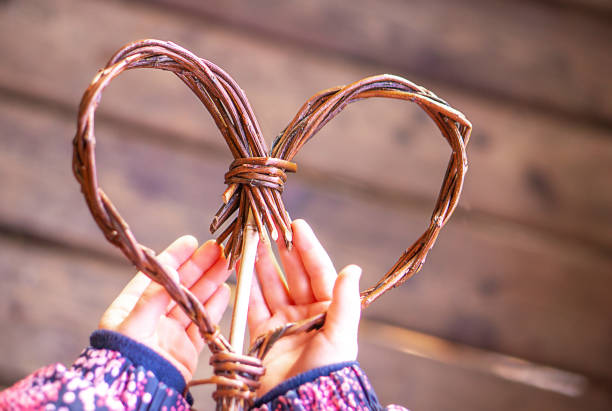 Brown wooden heart in child hands on the brown vintage wooden background. Copy space.