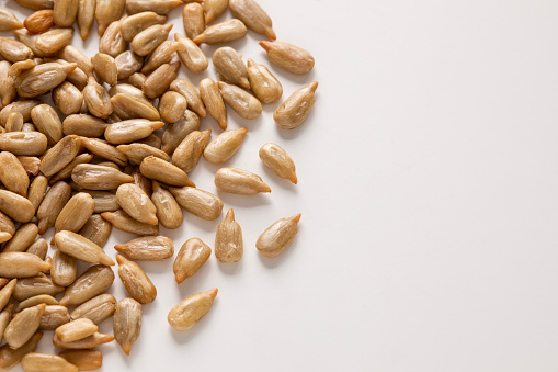 Closeup top view of roasted sunflower seeds on white background with a copy space