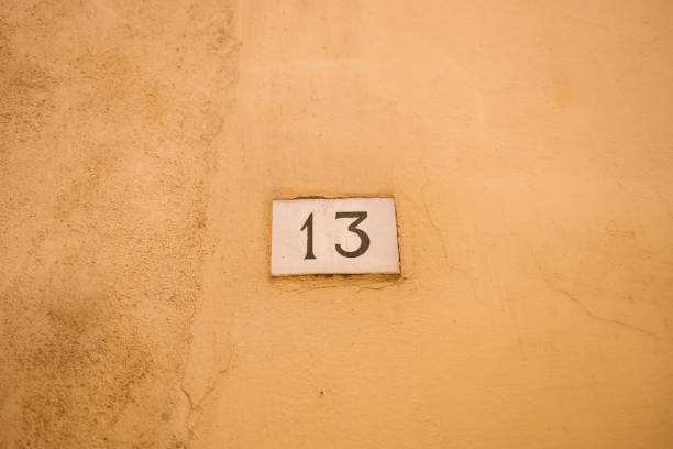 House number 13 on on a red stone wall. Thirteen with copy space. High quality photo
