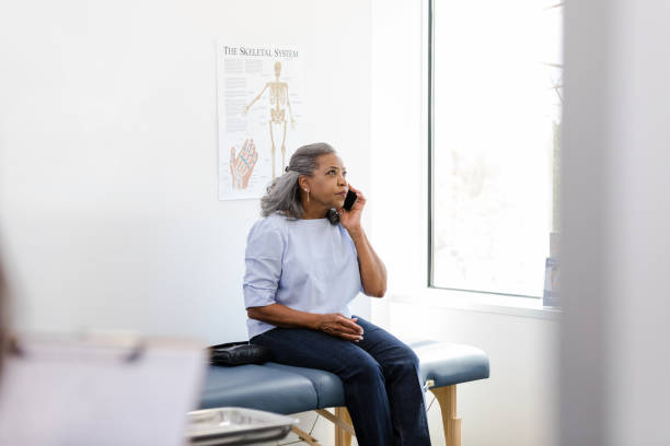 istock Senior woman makes phone call while waiting in examination room 1483293081