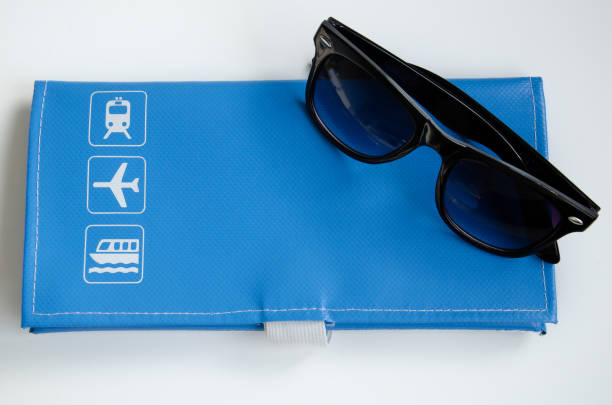 A blue travel wallet with black sunglasses on a white background
