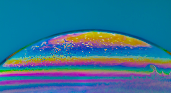 Vivid rainbow colours of a Macro soap bubbles creating psychedelic patterns under light dome washing shop and detergent bubbles