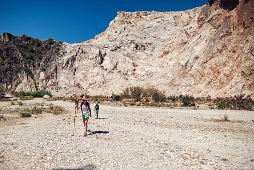 Mother and three kids hiking on a rocky path in Andalusia mountains. Two boys are aged 7 and the girl is 10.\nSunny summer day.\nNikon D800