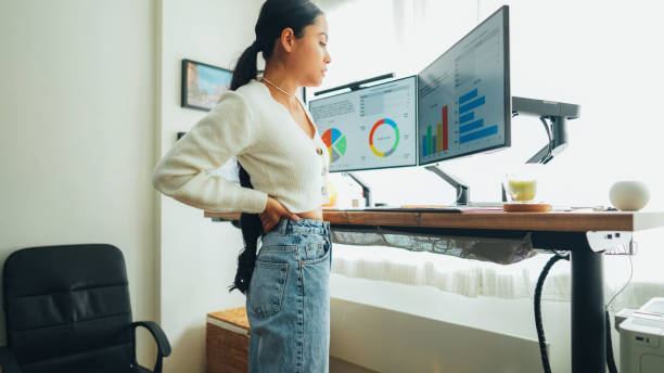 istock Woman with back pain working at standing desk home office 1483296779