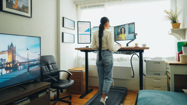 Woman at standing desk home office talking on business video call stock photo