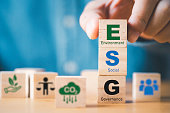 Businessman assemble ESG wording on wooden cube block for sustainable organization development and corporation of Environment Social Governance concept.
