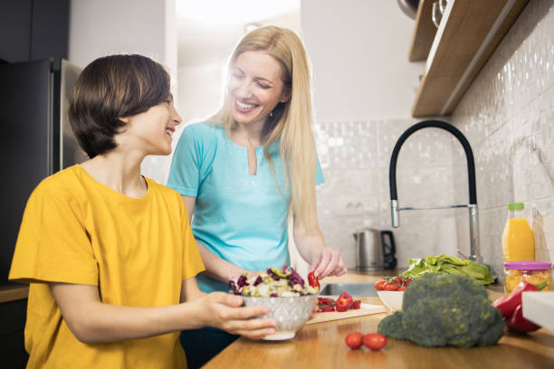 istock Happy woman preparing salad with her son 1483299677